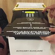 Insertion d'un bulletin de vote dans une tabulatrice au Nouveau-Brunswick