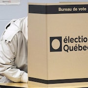 Un électeur derrière un isoloir en carton.