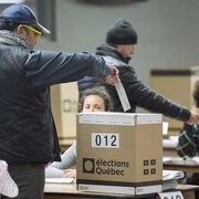 Un électeur glisse son bulletin de vote dans une boîte prévue à cet effet.