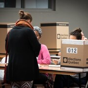Une électrice attend de recevoir des documents des scrutatrices.