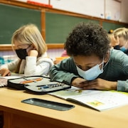 Des élèves portant un masque dans une salle de classe d'une école primaire.