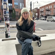 Emma Girard est assise sur un banc dehors.