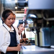 Une jeune femme manipule une machine à café.