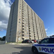 Une voiture de police est stationnée devant un immeuble à logements de 18 étages.