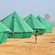 Un enfant se promène dans un camp de fortune. 