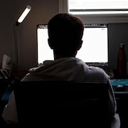 Un enfant suit son cours en ligne devant un écran d'ordinateur.