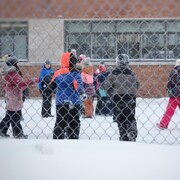 Des enfants dans une cour d'école en hiver.