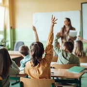 Une élève lève la main en classe.