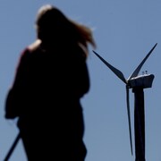 Une femme passe devant une éolienne le 23 avril 2021 à Londres, en Angleterre.