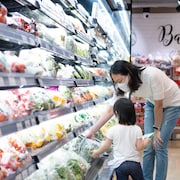 L'allée des légumes réfrigérés au supermarché; une mère et son enfant choisissent une laitue.