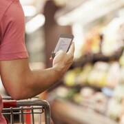 Un homme consulte sa liste d'épicerie sur son cellulaire alors qu'il marche dans un supermarché.