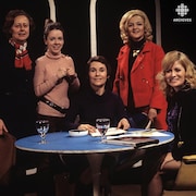 Dans un studio de télévision, Yvette Pard et Francine Bordeleau, Françoise Faucher, Madeleine Gobeil et Aline Desjardins sont rassemblées autour d'une table sur laquelle reposent documents, cendrier et verres d'eau.