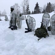 Des raquettes militaires sont plantées dans un banc de neige.