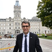 Éric Duhaime sourit devant l'édifice de l'Assemblée nationale du Québec.