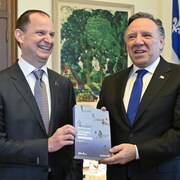 Messieurs Girard et Legault, côte à côte, tiennent dans leurs mains le document du budget 2023-2024.