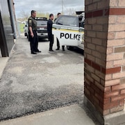 Un homme et deux policiers près d'une voiture de police.