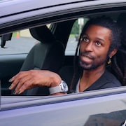 Un montage de photos, derri&egrave;re : un homme assis dans sa voiture. Devant, un homme, le journaliste Louis Blouin, regarde l'objectif de la cam&eacute;ra.