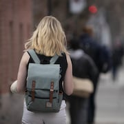 Une étudiante vue de dos marche dans une rue montréalaise. 