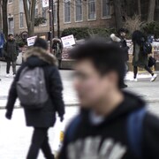 Une foule d'étudiants déambulent sur un campus universitaire en hiver.