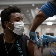 Un jeune homme reçoit une dose de vaccin.