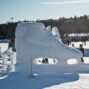 Sculpture de glace en forme de patin avec des personnes autour. 