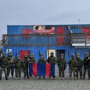 Un camion militaire et des soldats en uniforme qui tiennent un drapeau.
