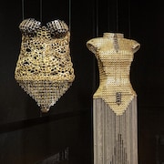 Quatre sculptures représentant des corsages sont suspendues dans une salle d'exposition. 