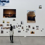 Une personne regarde un mur couvert de photos dans un musée.