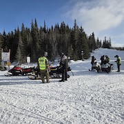Des patrouilleurs de la Sûreté du Québec parlent avec des motoneigistes.