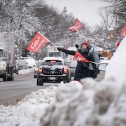 Des grévistes manifestant en bordure d'une route à Montréal.