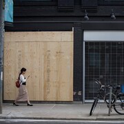 Une femme passe devant la façade d'un commerce placardé