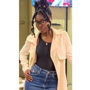 Une jeune femme à la peau noire a des cheveux noirs tressés et les yeux bruns. 