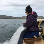 Une femme inuite sur un bateau regarde au large