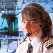 Une jeune femme dans un habit de pilote dans une cabine de pilotage.