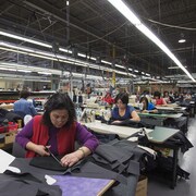 Des femmes cousent des manteaux dans un atelier de Toronto.