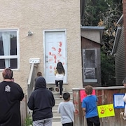 Les manifestants couvrent sa porte d'empreintes de mains rouges avec de la peinture lavable. 