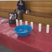 Les photos de Morgan Beatrice Harris et de Marcedes Myran sont disposées sur une table recouverte d'une nappe rouge, sur laquelle se trouvent des bougies. 