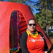Angella Lavallee se tient devant une structure rouge. 