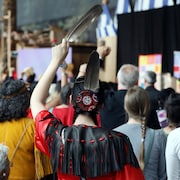 Une femme de dos tient une plume d'aigle pendant la cérémonie de fermeture de l'Enquête nationale sur les femmes et les filles disparues et assassinées.
