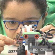 Jeune femme travaillant sur un robot.