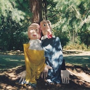 Deux marionnettes géantes appuyées sur un arbre.