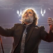 Un homme chante en levant la tête et les bras dans les airs.