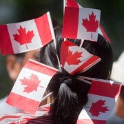 Une femme avec des drapeaux du Canada dans les cheveux. 