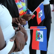 Des femmes tiennent des drapeaux haïtiens à l'intérieur du Théâtre Cercle Molière à Winnipeg.