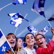 Une foule brandit des drapeaux québécois.