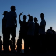 Silhouettes d'adolescents rassemblées au coucher de soleil. 