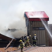 Pompiers sur un toit enfumé.