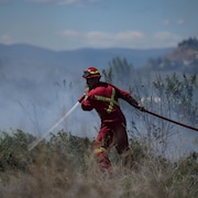 Un pompier arrose de l'herbe en feu à Kamloops, en Colombie-Britannique, le 5 juin 2023.