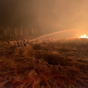 Des pompiers essayent d'éteindre un feu, la nuit, en Alberta, le 7 mai 2023.