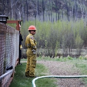 Un pompier surveille un tuyau d'arrosage dans le quartier évacué de Grayling Terrace, à Fort McMurray (Alberta), le jeudi 16 mai 2024.